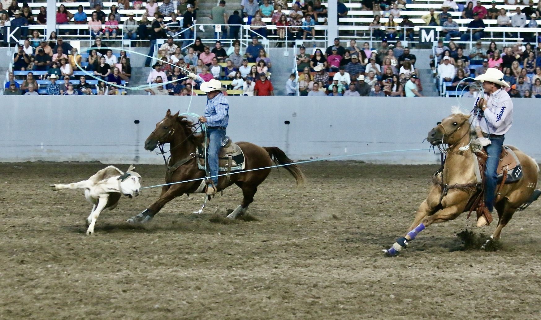Two men paddle boarding against a sunset on a glassy lake